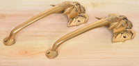 Golden brass door handle pair, wall-mounted curved levers with Ganesha face ends