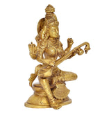 Brass Saraswati idol angled view, seated goddess with raised arms and veena