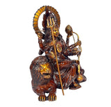 Brass Durga idol with tall circular halo, one hand holding trident, lion at feet