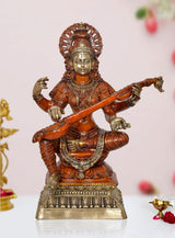 Brass Saraswati statue seated on pedestal, holding veena, ornate gold accents