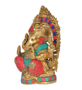 Brass Ganesha statue side view, raised hand, gold ornaments and red-teal clothing