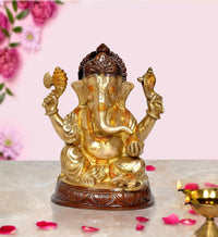Gold-tone brass Ganesha idol with raised arms, seated on a carved base