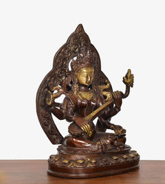 Brass Tara Devi statue angled view, golden face with raised hand holding a staff