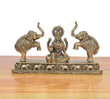 Seated Lakshmi idol with crown and jewelry, flanked by two elephants on detailed base.