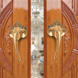 Brass Ganesha face door handle with ornate gold-tone lever on a wood door