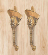 Two gold brass man-face door handles on pale wood, arched turban head design