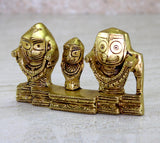 Golden brass idol from front-left angle: three figures with circular eye motifs