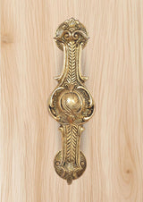Ornate brass door handle, golden finish, decorative grip and top flourish