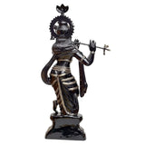Brass Krishna statue in profile, flute raised, detailed jewelry, dark pedestal