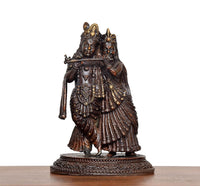 Brass Radha Krishna idol, front view with raised arms, crowns, and layered jewelry details.