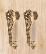 Close-up: brass Ganesha face door handle pair, engraved ornamented heads.