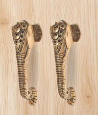 Close-up: brass Ganesha face door handle pair, engraved ornamented heads.