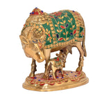Brass cow and calf statue, close-up of green cloth motif with gold beads and blue eyes