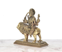 Durga Maa on lion idol in side view, holding trident and a conch-like object