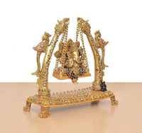 Angled view brass Ganesha swing idol with multicolor meenakari on the jhula base