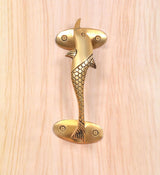 Close-up golden brass dolphin fish door handle with scale-textured body and screws
