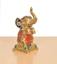 Brass elephant figurine angled view, raised trunk, blue-gold ears, multicolor accents