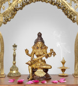 Brass Saraswati idol of seated Hindu goddess holding veena, detailed gold-and-brown finish