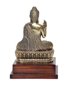 Rear view brass Buddha statue with raised hand in Abhaya mudra on wooden base
