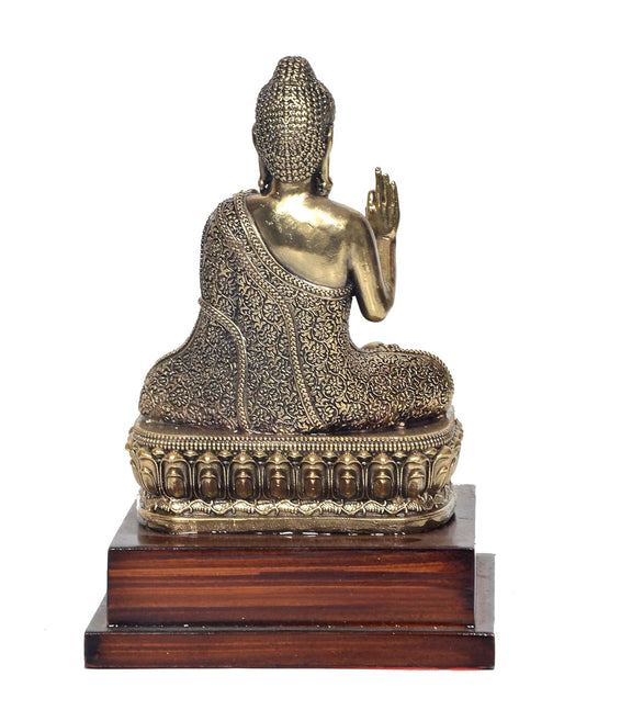 Rear view brass Buddha statue with raised hand in Abhaya mudra on wooden base
