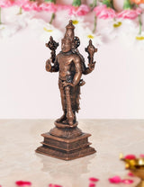 Copper Vishnu statue side view, standing with tall crown, holding ceremonial weapons