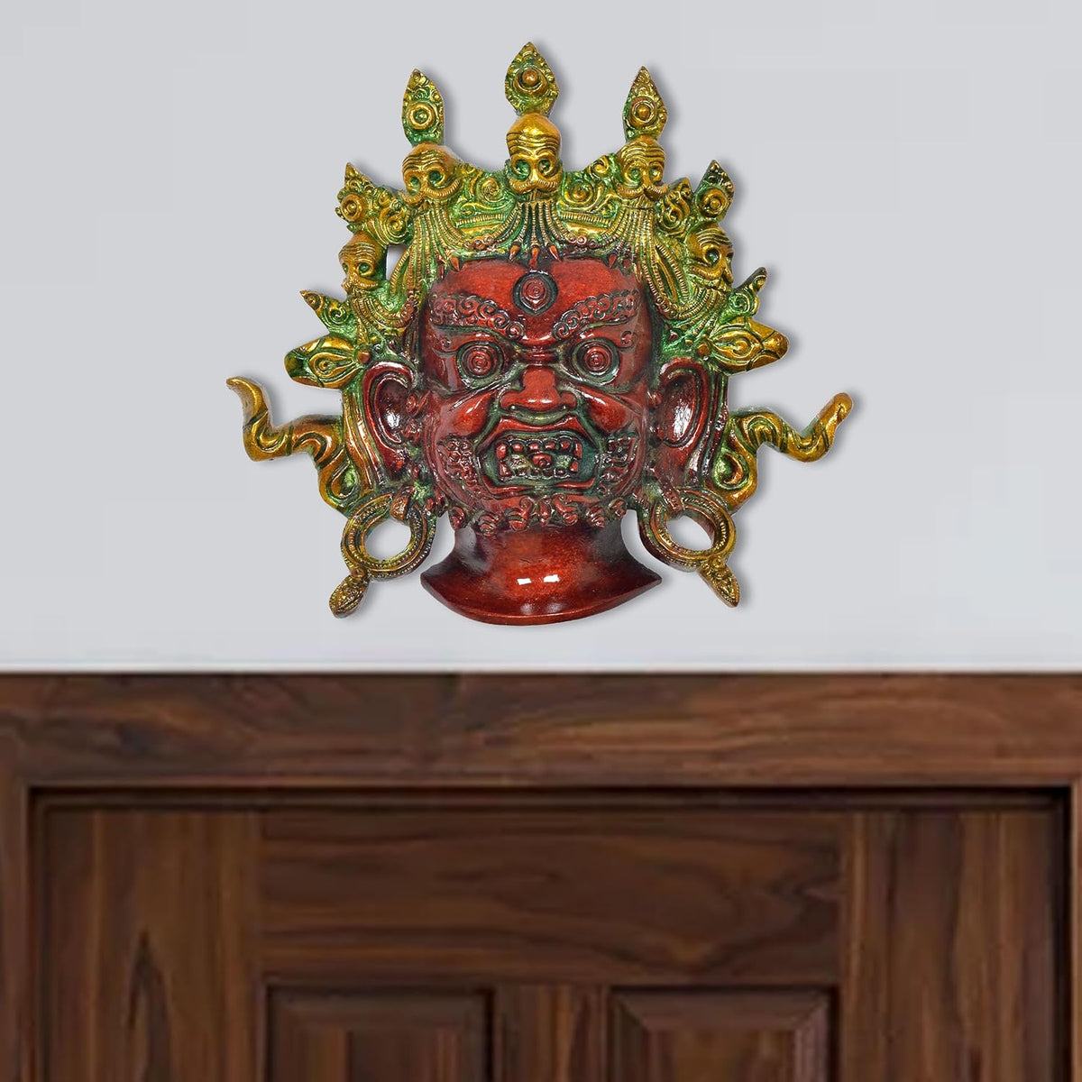 Brass Mahakala wall hanging with green-gold detailing and red face, multicolour