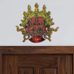 Brass Mahakala wall hanging with green-gold detailing and red face, multicolour