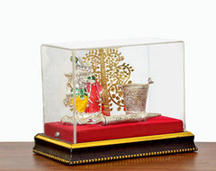 Radha-Krishna figurine under ornate tree in clear glass box, red base with gold trim
