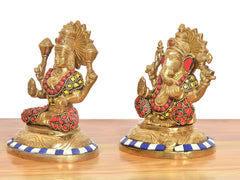 Two brass statues of Lakshmi and Ganesha, side view with red bead accents.