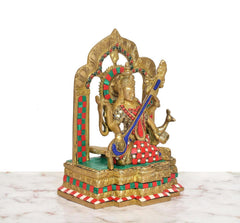 Maa Saraswati brass statue from front-right angle, seated on carved pedestal, blue veena
