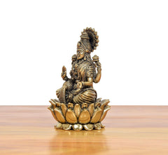 Side view bronze Lakshmi statue seated on lotus base, sculpted crown and ornaments.