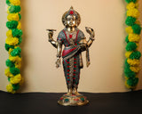 Brass Dhanvantari statue with red-green stonework; four-armed physician deity pose