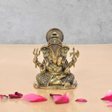 Brass Lord Ganesha idol with four arms, seated posture, ornate details on base