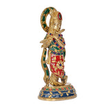 Brass Krishna idol statue, profile view with green halo and red robe, on round base