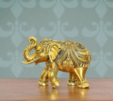 Golden brass elephant figurine with ornate patterned back and raised trunk, side view.