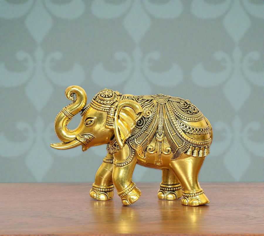 Golden brass elephant figurine with ornate patterned back and raised trunk, side view.