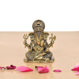 Brass Lord Ganesha idol, seated with raised hands and detailed crown, round patterned base