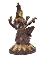 Brass Saraswati idol seated on lotus, side view with veena and ornamental details.