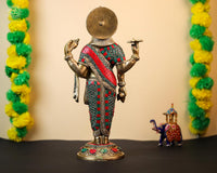 Rear view of brass Dhanvantari statue with jeweled red-green draped garment