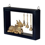 Nandi idol statue with raised trunk in dark frame, multiple brass bells hanging, 9 in