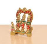Side view of brass Ram Darbar idol with arched backdrop and three painted figures
