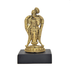 Golden standing deity idol wearing crown and ornate draped garment, on pedestal