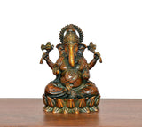 Seated brass Lord Ganesha idol on base, four arms raised, ornate jewelry and crown detail