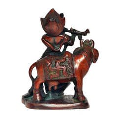 Rear three-quarter view of Krishna on cow idol, ornate patterned attire