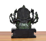Brass Ganesha idol rear view with round halo disc and multi-armed attendants on pedestal