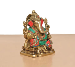 Brass Ganesh murti angled view, teal and red jeweled clothing with gold hands