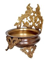 Brass peacock urli on dark base with decorative side filigree and rim