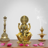 Golden brass Lakshmi statue with raised hands, seated on lotus