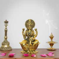 Golden brass Lakshmi statue with raised hands, seated on lotus