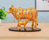 Resin Kamdhenu cow statue with calf, multicolor painted design on a round base.